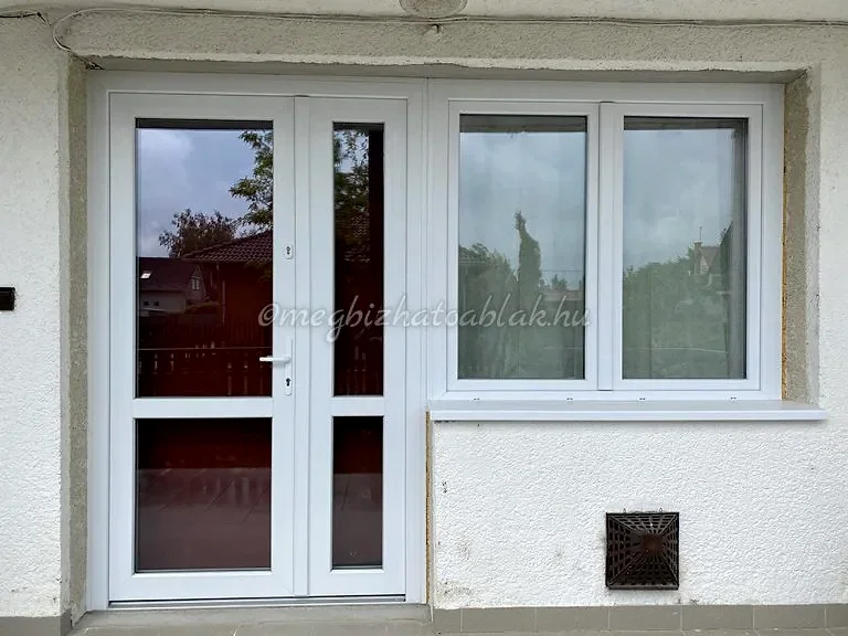 Fehér színű kétszárnyas műanyag ablak bejárati ajtóval